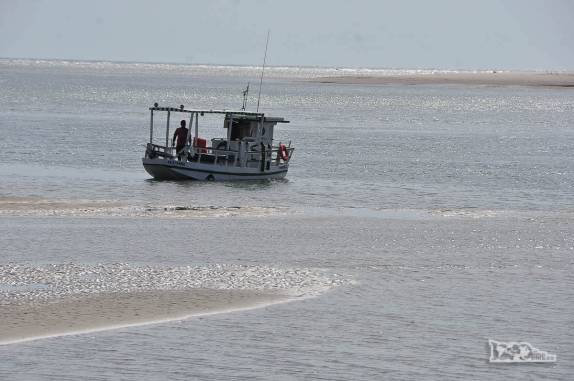 Um barco navega pelo rio que divide as praias de Fortim e Canoa Quebrada, no litoral do Ceará